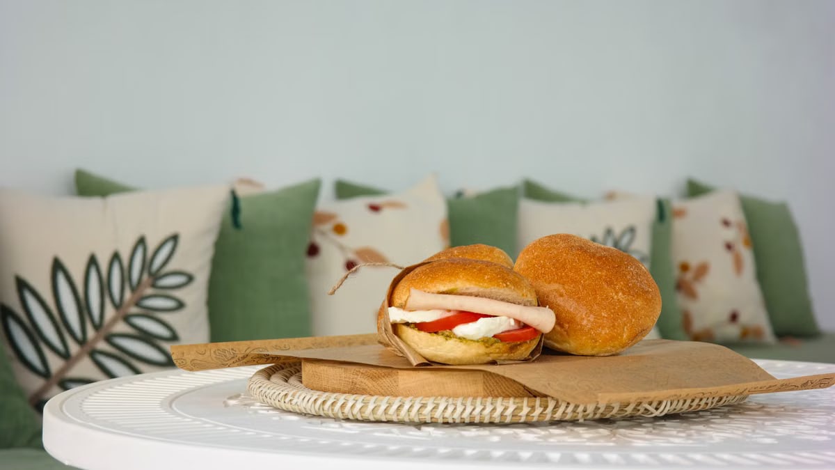 Fresh sandwich with mozzarella and tomato on a stylish patio setting with decorative pillows.